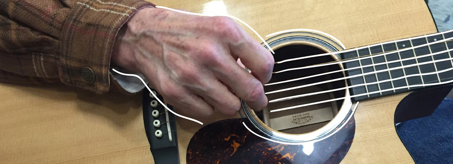 A patient in the Natalie Kutner Palliative Care Creative Arts Therapy Program plays the guitar.
