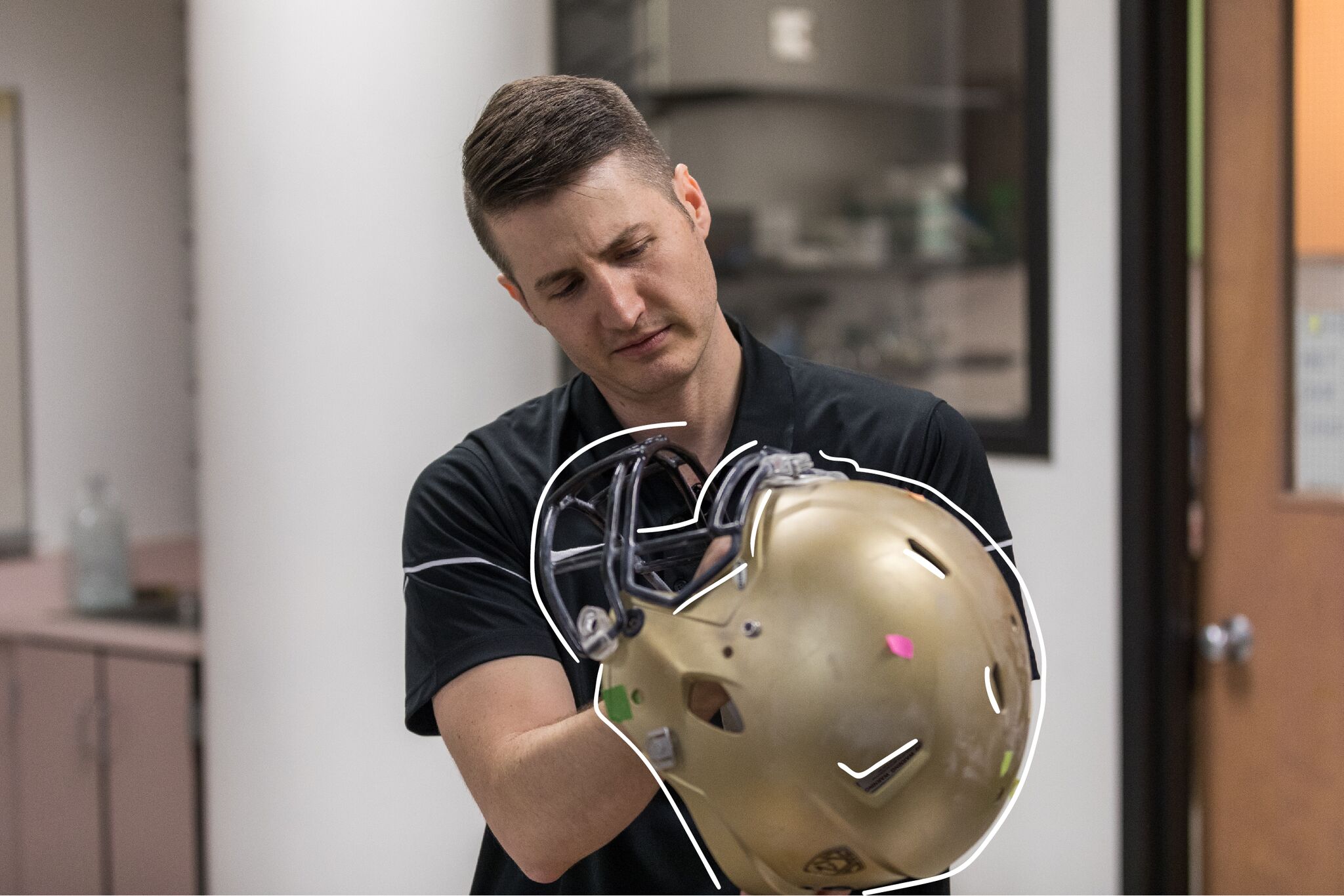 Associate Professor Chris Yakacki inspects a football helmet in the SMAB lab at CU Denver. His startup company uses a lab-developed liquid-crystal foam technology for a better football helmet. (Photo courtesy of CU Denver)